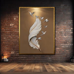 Puede incluir: Una obra de arte enmarcada que presenta una gran pluma blanca con un diseño curvo y varias aves plateadas en vuelo. La obra de arte está sobre un fondo marrón con un marco dorado, exhibida en una pared de ladrillo.