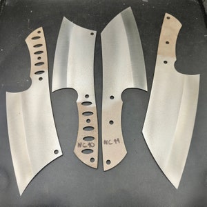 May include: Four silver metal knife blades with rounded tips and handles. The blades are marked with the letters "NC" followed by a number.