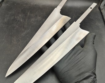 May include: Two long, silver, kitchen knives with a textured finish. The knives are laid on top of each other and held in a gloved hand.