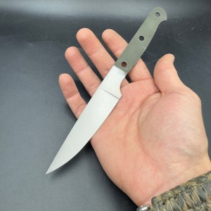 Könnte beinhalten: Ein silbernes Messer mit grünem Griff und abgerundeter Spitze. Das Messer wird in einer Hand gehalten.