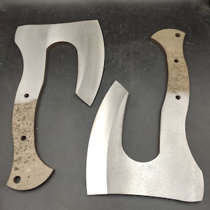 May include: Two silver-colored hand-forged axes with wooden handles. The axes have a curved blade and a rounded handle.