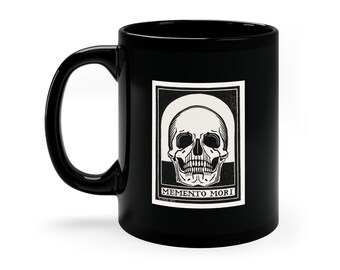 May include: Black ceramic mug with a white skull and bones graphic and the text "MEMENTO MORI" printed on the front.