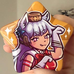 May include: A star-shaped pin featuring a cartoon character with white hair, a red bow, and a gold crown. The pin has a gold background with white star accents and a glossy finish. The character is wearing a red and white outfit.