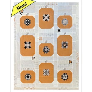 Peut inclure: Une courtepointe faite à la main avec des citrouilles orange et des centres en forme d'étoile. Les citrouilles sont disposées sur un fond blanc avec des carrés à motifs. Une bannière jaune dans le coin indique "New!"