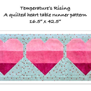 Könnte beinhalten: Ein gequiltetes Tischläufer-Muster mit drei rosa und roten Ombre-Herzen auf einem hellblauen Hintergrund mit einem weißen Blumenmuster. Das Muster trägt den Titel "Temperature's Rising" und misst 16,5 Zoll mal 42,5 Zoll.