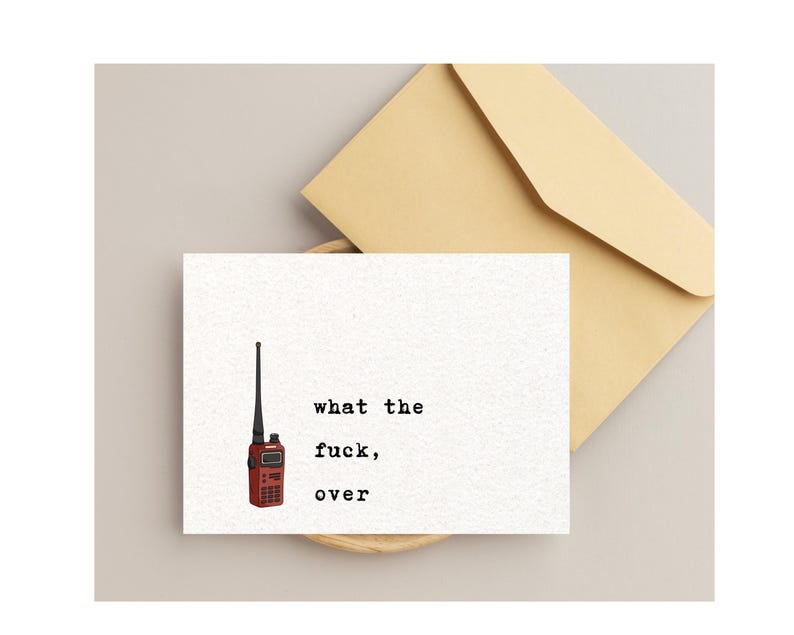 Pu&ograve; includere: Un biglietto di auguri bianco con la scritta "what the fuck, over" e un'illustrazione di walkie-talkie rosso. Una busta beige &egrave; dietro il biglietto. Il biglietto &egrave; su una superficie beige chiaro.