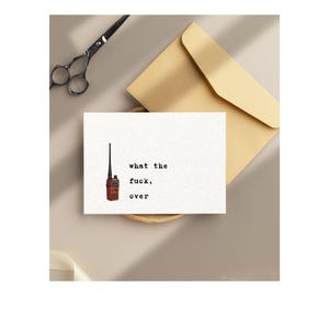 Pu&ograve; includere: Un biglietto di auguri con il testo "what the fuck, over" e un'illustrazione di walkie-talkie rosso. Il biglietto &egrave; su una superficie neutra con una busta beige e forbici.