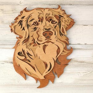 May include: A wooden wall art piece depicting a dog's head. The artwork is made of layered wood in shades of brown and tan, creating a three-dimensional effect. The dog's features, including its eyes, nose, and fur, are intricately detailed.