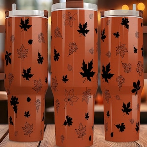 May include: Three stainless steel tumblers with a brown exterior and black leaf designs. The tumblers have lids and handles.
