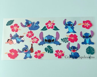 Op de afbeelding: Een vel stickers met de blauwe alien Stitch uit Lilo & Stitch. De stickers tonen Stitch in verschillende poses, samen met roze hibiscusbloemen en groene bladeren. De tekst "Craftywrapdesigns" is zichtbaar.