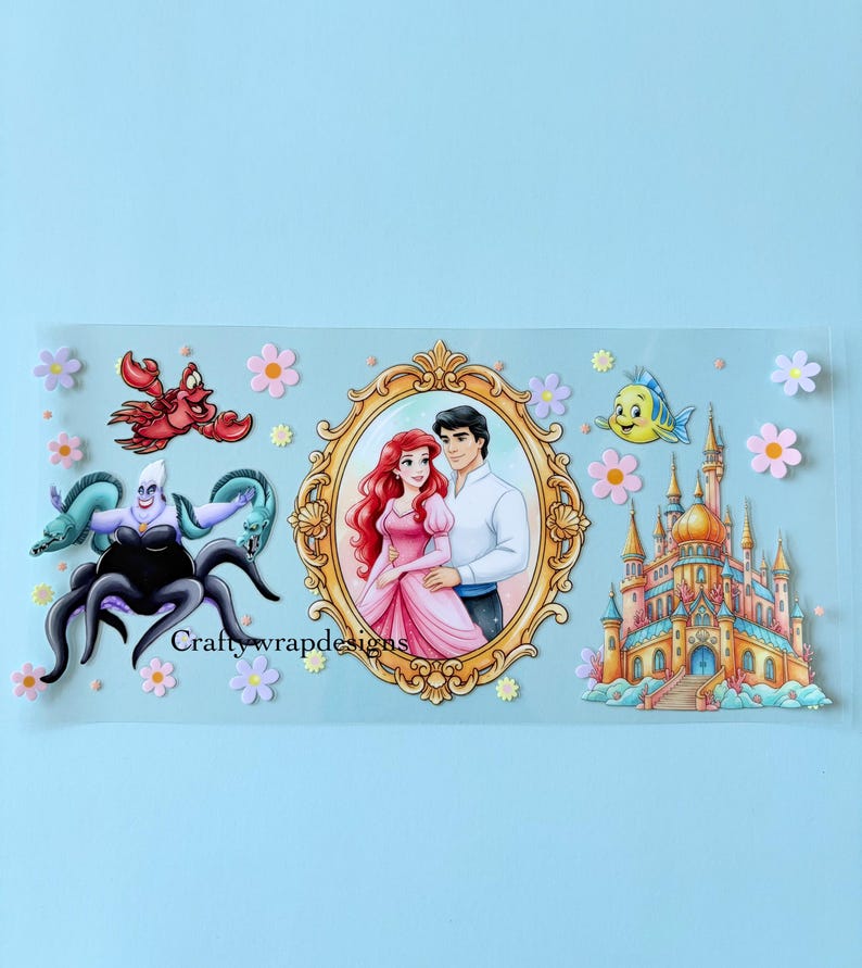 May include: A clear sticker featuring characters from The Little Mermaid. The design includes Ariel and Prince Eric in a gold frame, Ursula, Sebastian, Flounder, and a castle. The sticker is decorated with pink and purple flowers, and the text "Craftywrapdesigns" is visible.