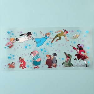May include: A clear sticker featuring characters from Peter Pan, including Peter Pan, Wendy, Captain Hook, and Tinkerbell. The sticker has a light blue background with blue star accents and the text "craftywrapdesigns".