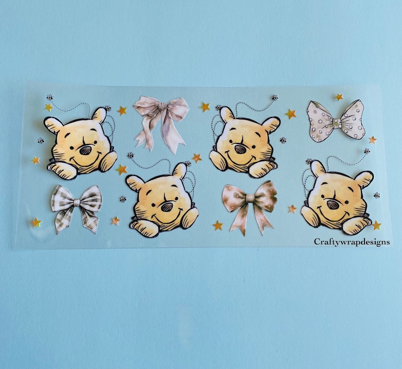 May include: A sheet of clear sticker paper with four Winnie the Pooh bear stickers and three bow stickers. The stickers are on a light blue background. The text "Craftywrapdesigns" is at the bottom of the sheet.