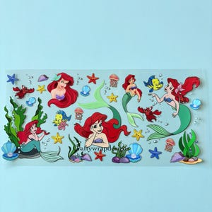 K&ouml;nnte beinhalten: Ein Stickerbogen mit Ariel aus Arielle, die Meerjungfrau. Die Sticker zeigen Ariel mit roten Haaren und einem gr&uuml;nen Schwanz, sowie andere Meereskreaturen wie Seesterne, Krabben und Quallen. Die Sticker befinden sich auf einem transparenten Hintergrund.
