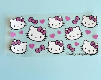 Op de afbeelding: Een vel doorzichtig plakpapier met roze en witte Hello Kitty stickers. De stickers tonen Hello Kitty's gezicht met een roze strik en roze hartjes.