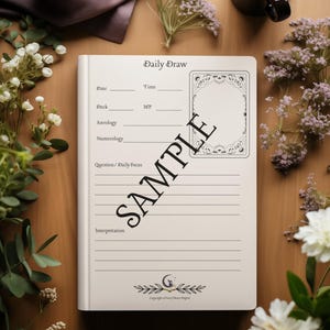 May include: A cream-colored Daily Draw journal with lined pages and a decorative card outline. The journal is open, displaying the text "Daily Draw" and prompts for date, time, and interpretation. The word "SAMPLE" is printed across the pages. The journal is surrounded by flowers and a cup of coffee.