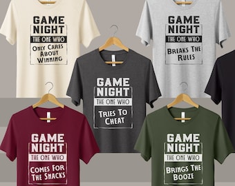 May include: Six different t-shirts with the text "Game Night" and a different slogan on each shirt. The slogans are "The one who only cares about winning", "The one who comes for the snacks", "The one who tries to cheat", "The one who breaks the rules", "The one who brings the booze", and "The one who doesn't like to lose".