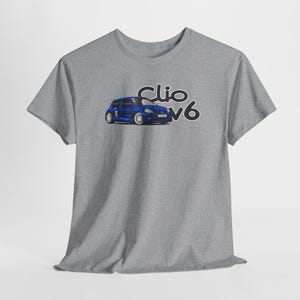 Può includere: T-shirt grigio con grafica di un'auto blu e la scritta "Clio V6" in nero. L'auto è una piccola berlina sportiva con ruote bianche. La maglietta è realizzata in un materiale morbido e confortevole.