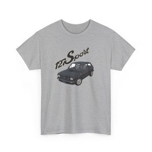 Puede incluir: Camiseta gris con un gráfico de un coche negro vintage y el texto "127 Sport". La ilustración del coche es detallada, y la camiseta tiene un diseño clásico de cuello redondo. El texto es en negro y dorado.