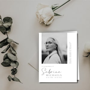 May include: A black and white photo memorial card with a portrait of a woman wearing glasses. The text reads "In loving memory of Sabrina Michaels 01.01.1940 - 03.04.2023".