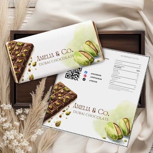 May include: A bar of Amelia & Co. Dubai Chocolate with pistachios, presented on a white package with the brand name and a watercolour pistachio design. A nutrition facts sheet and social media icons are also visible.
