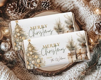 May include: Two rectangular Christmas-themed cards with the text "Merry Christmas" in gold script. One card features a Christmas tree with ornaments, the other has a tree, gifts, and the text "from The Wilsons". The cards are on a wooden slice.