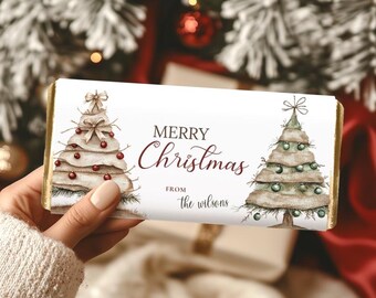May include: A white chocolate bar with gold foil edges, featuring watercolor Christmas trees and the text "MERRY Christmas" and "from the wilsons". The trees are decorated with red and green ornaments.