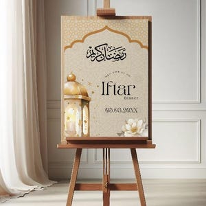 May include: A gold easel with a sign that says "Welcome to our Iftar Dinner 05.03.20XX". The sign has a gold and white design with an ornate lantern and flowers.