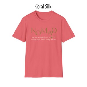 May include: Coral silk-colored t-shirt with the word "NOMAD" in gold lettering. Below the word, the text reads "Some souls are simply born to go collecting stories, moments, learnings and miles."