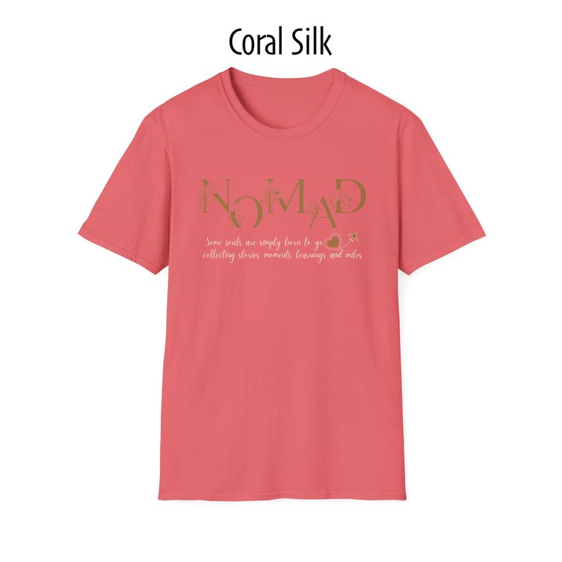 May include: Coral silk-colored t-shirt with the word "NOMAD" in gold lettering. Below the word, the text reads "Some souls are simply born to go collecting stories, moments, learnings and miles."