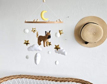 May include: A hanging mobile featuring a central brown dog figure surrounded by white felt clouds, gold metallic stars, and a yellow crescent moon suspended from a circular wooden frame with small wooden beads and white string.