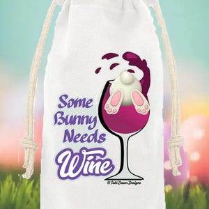 Op de afbeelding: Witte wijnfleszak met een trekkoordsluiting. De tas heeft een afbeelding van een konijn in een wijnglas met de tekst "Some Bunny Needs Wine". Het ontwerp bevat paarse en roze accenten, perfect voor Pasen of een wijnliefhebber.