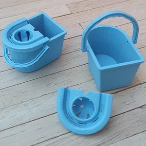 May include: A set of three light blue plastic dollhouse-sized cleaning buckets. The set includes a bucket with a wringer, a bucket with a handle, and a separate wringer.