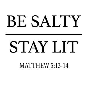 以下が含まれることがあります： 「BE SALTY STAY LIT」と「MATTHEW 5:13-14」というテキストが書かれた白黒のタイポグラフィー印刷です。