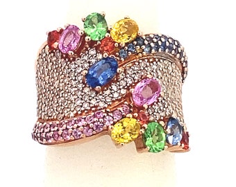 May include: A rose gold ring with a wave-like design set with a variety of colorful gemstones, including sapphires, emeralds, rubies, and diamonds.