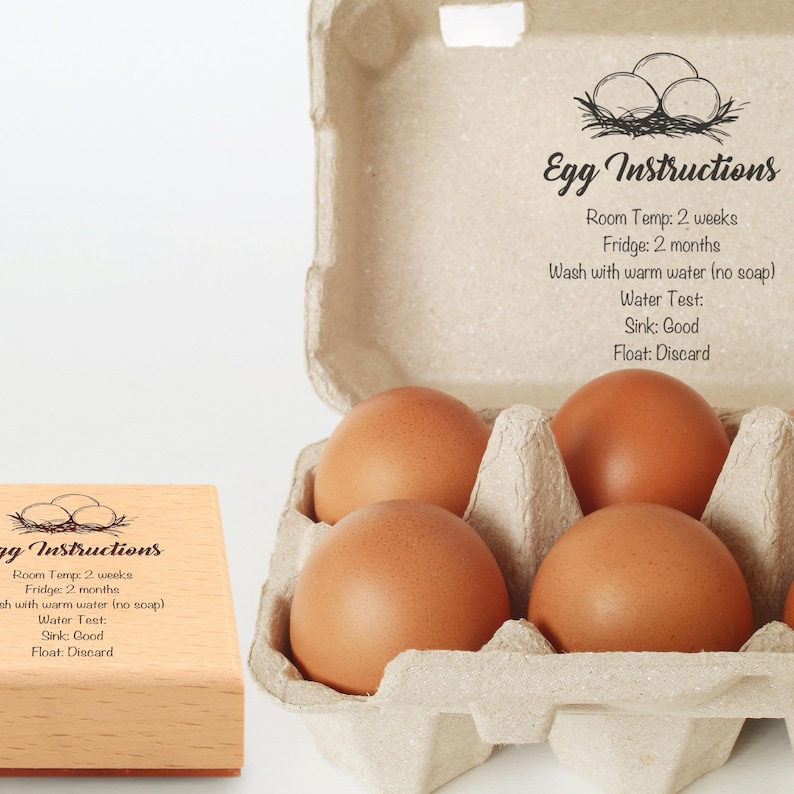 May include: A carton of brown eggs with the text "Egg Instructions". The instructions include room temperature and fridge storage times, and a water test. A wooden stamp with the same text is also visible.