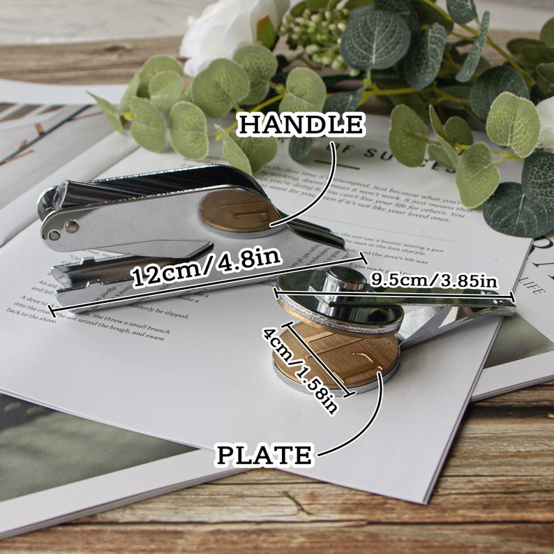 May include: A silver and gold metal stamp with a handle and a round plate. The handle is 12 inches long and the plate is 4 inches in diameter. The stamp is used for making impressions on paper or other materials.