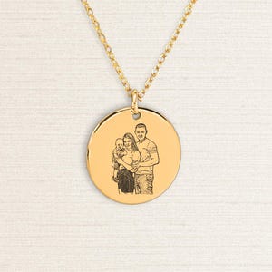 Könnte beinhalten: Eine goldfarbene Halskette mit einem runden Anhänger, der ein eingraviertes Familienporträt zeigt. Kette und Anhänger sind goldfarben. Das Porträt zeigt ein Paar und ein Kind.