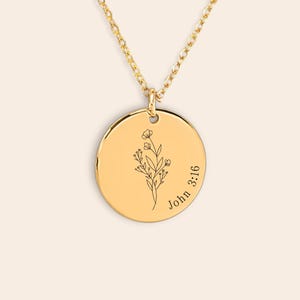 Könnte beinhalten: Eine goldfarbene Halskette mit einem runden Anhänger. Der Anhänger zeigt ein eingraviertes Blumendesign und den Text "John 3:16". Die Halskette ist ebenfalls goldfarben und hängt am Anhänger.