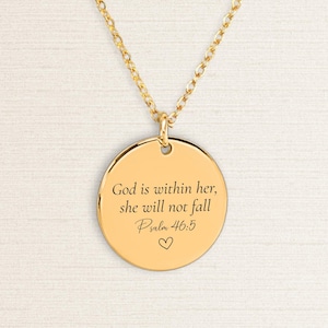 Peut inclure: Collier pendentif doré avec un charm rond. Le charm porte l'inscription "God is within her, she will not fall Psalm 46:5" et un petit symbole de cœur. Le collier a une chaîne délicate.