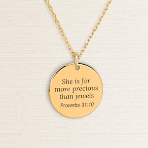 Op de afbeelding: Goudkleurige ketting met een ronde hanger. De hanger heeft de gegraveerde tekst "She is far more precious than jewels Proverbs 31:10". De ketting en hanger zijn glanzend goudkleurig.