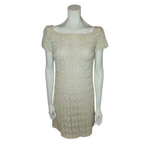 May include: A white crochet dress with a scoop neck and short sleeves. The dress is made of a delicate, open-weave fabric.