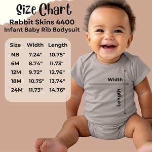 K&ouml;nnte beinhalten: Ein l&auml;chelndes Baby tr&auml;gt einen grauen Baby-Body. Das Bild enth&auml;lt eine Gr&ouml;&szlig;entabelle f&uuml;r den Rabbit Skins 4400 Baby-Ripp-Body, die Ma&szlig;e in Zoll f&uuml;r die Gr&ouml;&szlig;en NB bis 24M zeigt.