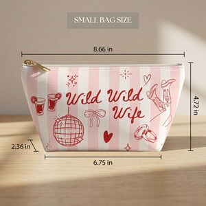 May include: A small, pink and white striped bag with the text "Wild Wild Wife" and illustrations of cocktails, a disco ball, boots, and rings. The bag measures 8.66 inches wide, 4.72 inches high, and 2.36 inches deep.