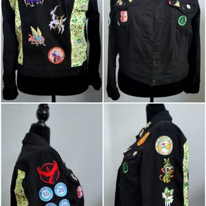 May include: A black denim jacket with various Pokemon patches and pins. The jacket has a green and yellow floral pattern on the sleeves. The back of the jacket has the name "TORI" embroidered on it.