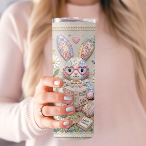 May include: A tall, insulated tumbler with an Easter bunny design. The bunny wears heart-shaped glasses and reads "Easter Stories" and "Quilt Stories". The tumbler has a floral and patchwork pattern in pastel colours.