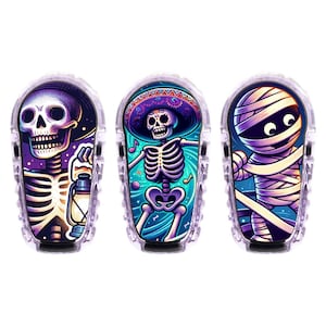 Könnte beinhalten: Drei farbenfrohe Halloween-Designs für ein medizinisches Gerät. Die Designs zeigen ein Skelett, das eine Laterne hält, ein Skelett, das mit einem Sombrero tanzt, und eine Mumie mit großen Augen.
