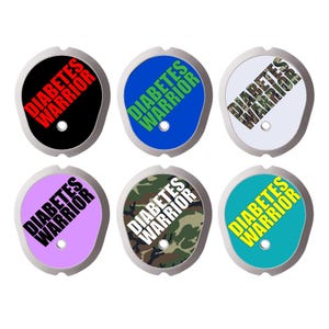 Puede incluir: Seis cubiertas adhesivas ovaladas para dispositivos médicos, cada una con un orificio central y el texto DIABETES WARRIOR. Los diseños incluyen negro con texto rojo, azul con texto verde, blanco con texto de camuflaje, morado claro con texto negro, camuflaje con texto blanco y verde azulado con texto amarillo.