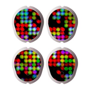 Op de afbeelding: Vier ronde, zilverkleurige, lichtgevende schijven met een zwarte achtergrond. Elke schijf heeft een ander patroon van rode, groene, blauwe, gele en paarse cirkels.