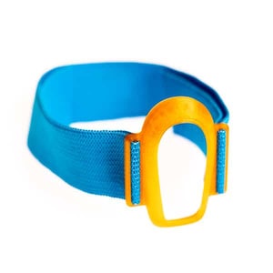 Könnte beinhalten: Ein leuchtend blaues elastisches Stoffband mit einem zentralen, U-förmigen Befestigungselement aus orangefarbenem Kunststoff. Das Band ist strukturiert gewebt und auf beiden Seiten mit dem orangefarbenen Teil verbunden, was eine Schlaufe bildet.